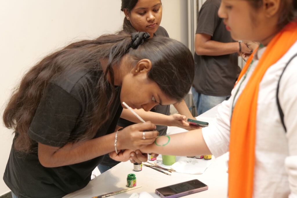 A participant painting a green design on a student’s arm