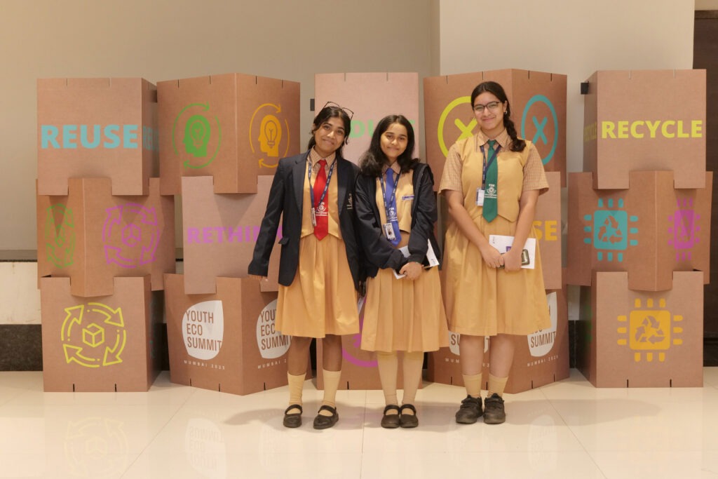 Three students beside reuse and recycle displays at Youth Eco Summit